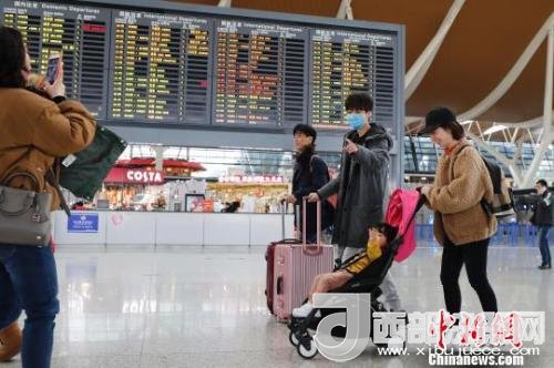 旅客帶著孩子前往辦票柜臺(tái)辦理登機(jī)手續(xù)?！∫罅⑶?攝