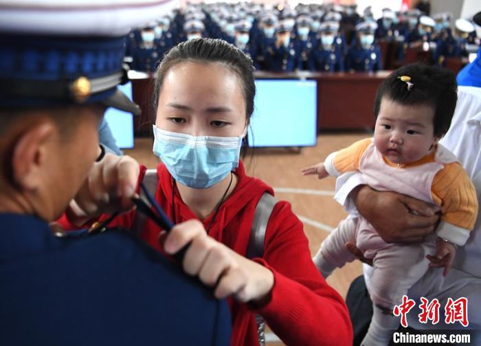 新消防員楊振的妻子彭莉與女兒現(xiàn)場見證丈夫加入“火焰藍(lán)”的神圣時刻?！⒅铱?攝